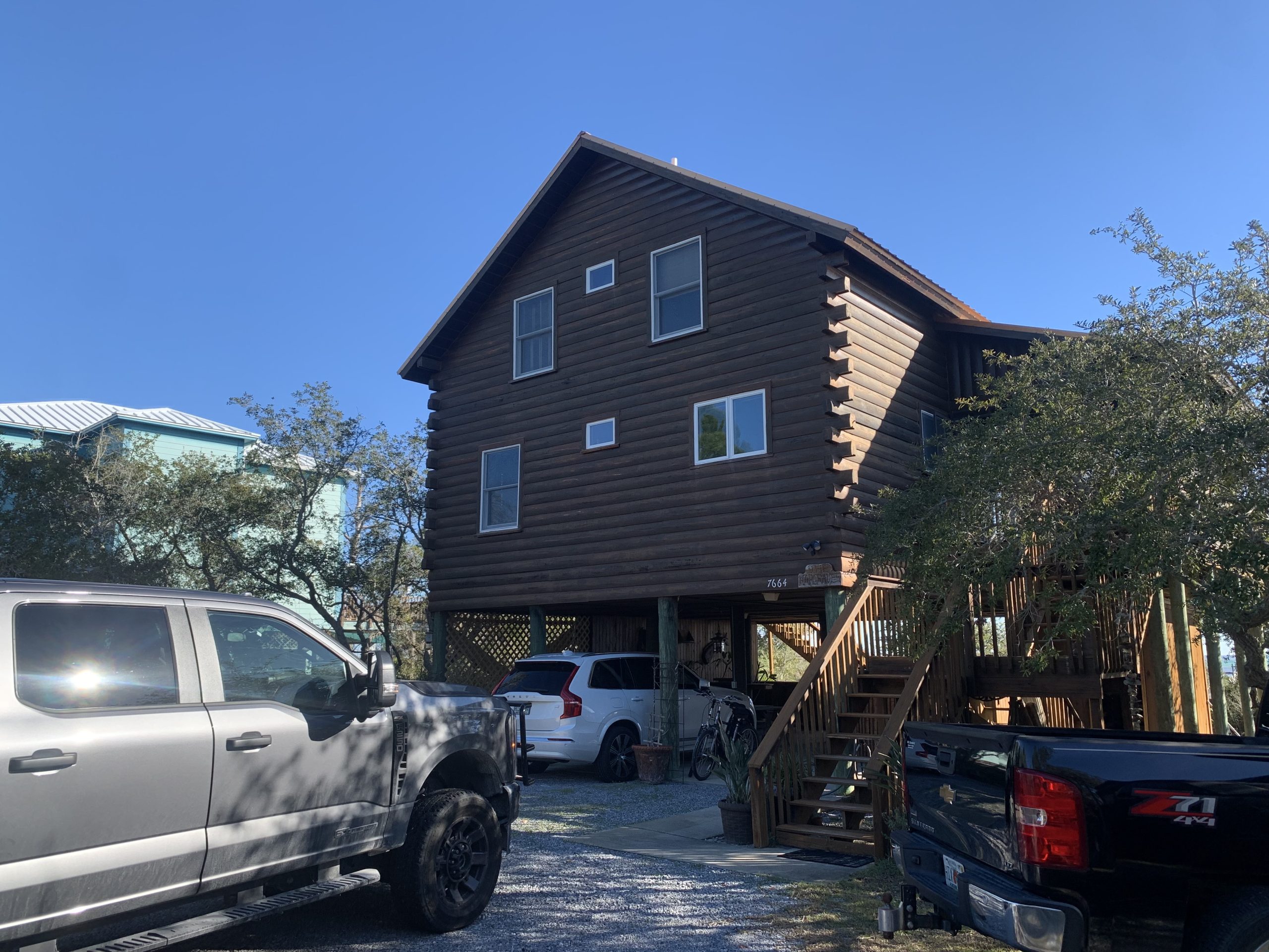 Before restaining: elevated log cabin on pilings with dark weathered stain
