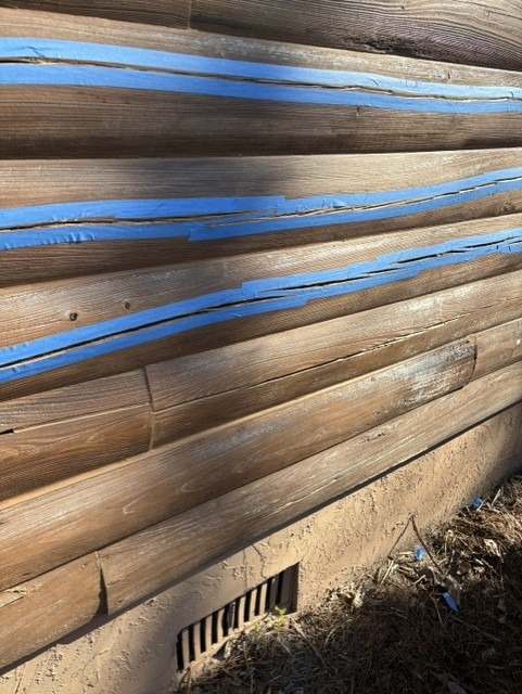 Log wall prepped with masking tape along open checks ahead of check filling