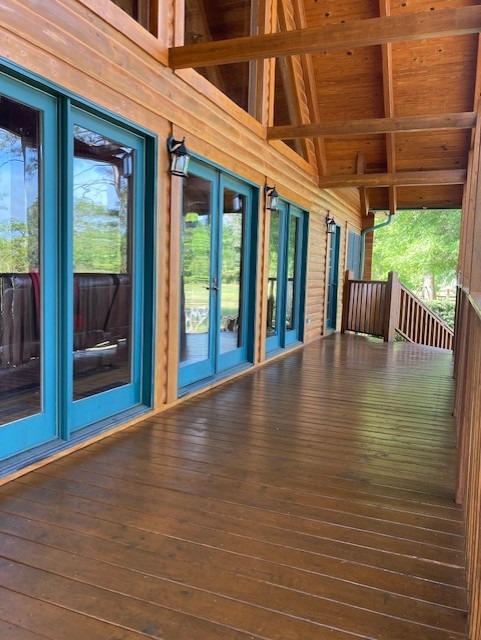 Wide covered deck of a restored log home with refinished decking