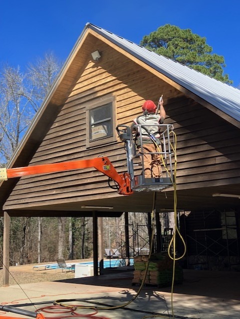 Crew member media blasting a log home gable from a boom lift