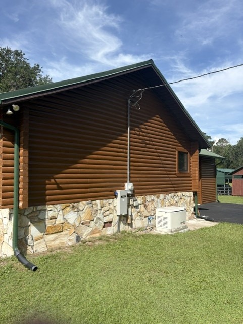 The same log home gable after restaining, with an even medium-brown finish