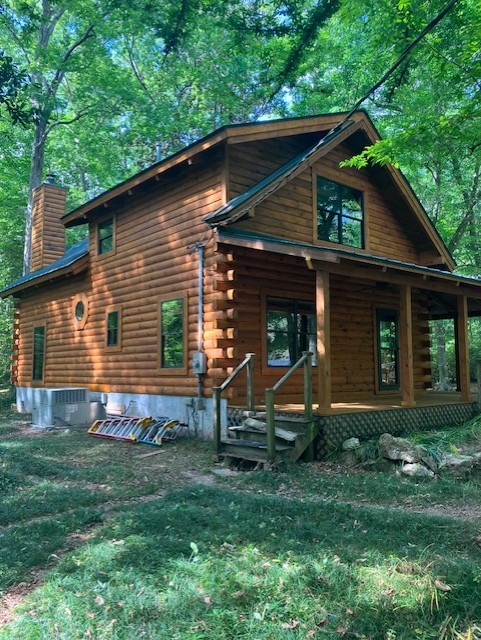 Side elevation of a restored log cabin with a covered porch