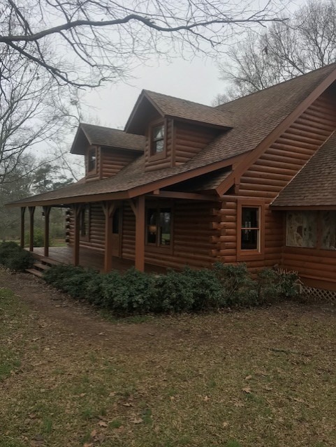 Front elevation of a restored log home with dormers and a porch