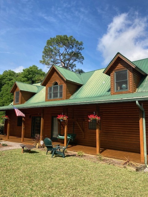 Restored log home with dormers and a green metal roof