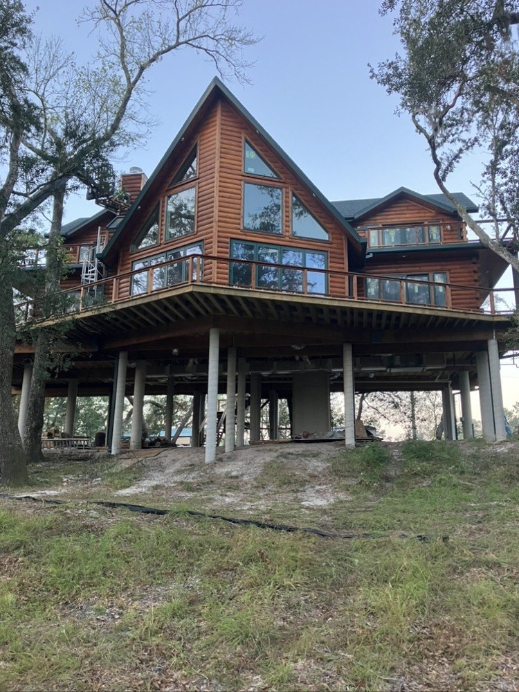 Restored log home raised on concrete pilings with a full wraparound deck
