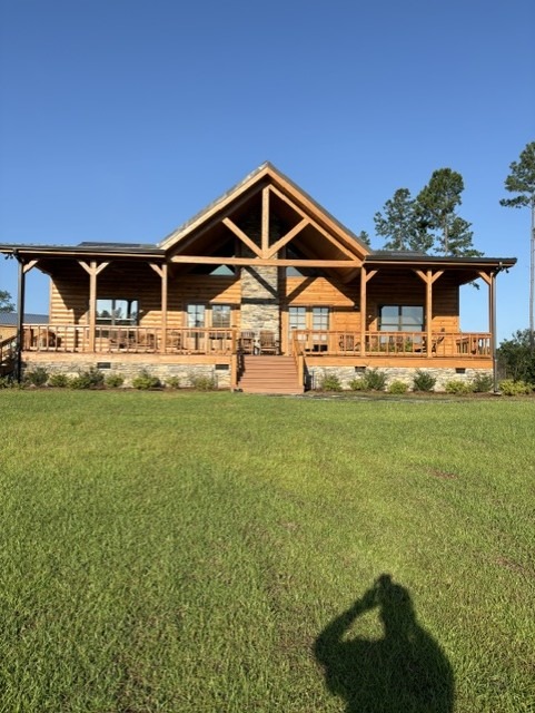 Restored log home front elevation with a timber truss gable and full porch