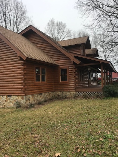 Restored log home gable above a stone skirt and covered porch