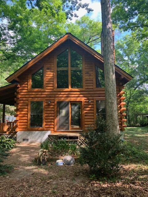 Restored log home with a prow front and tall windows set in the woods