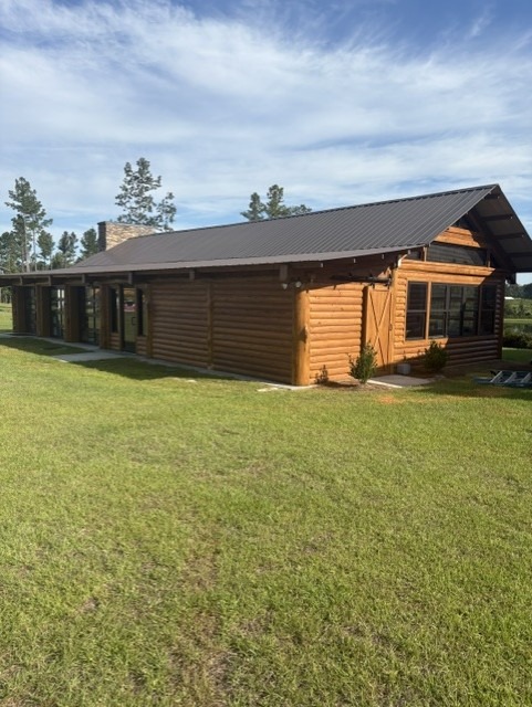 Single-story log home with a dark metal roof after restoration
