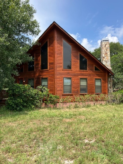 Restored log home gable beside a stone chimney