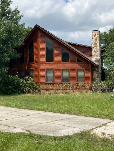 Two-story log home restored and restained, with a stone chimney