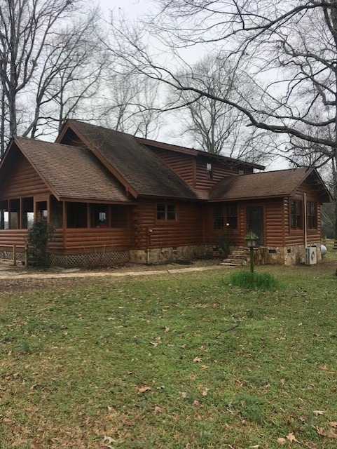 Log home with a tired, flattened finish before restoration work begins