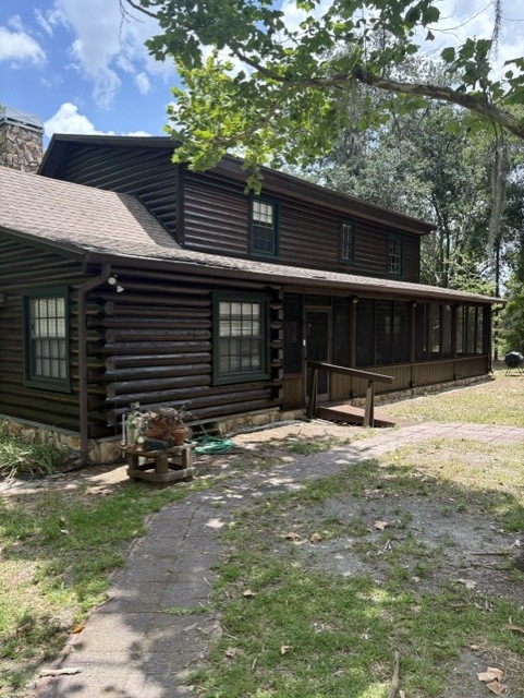 Two-story log home with a worn, darkened finish before restoration